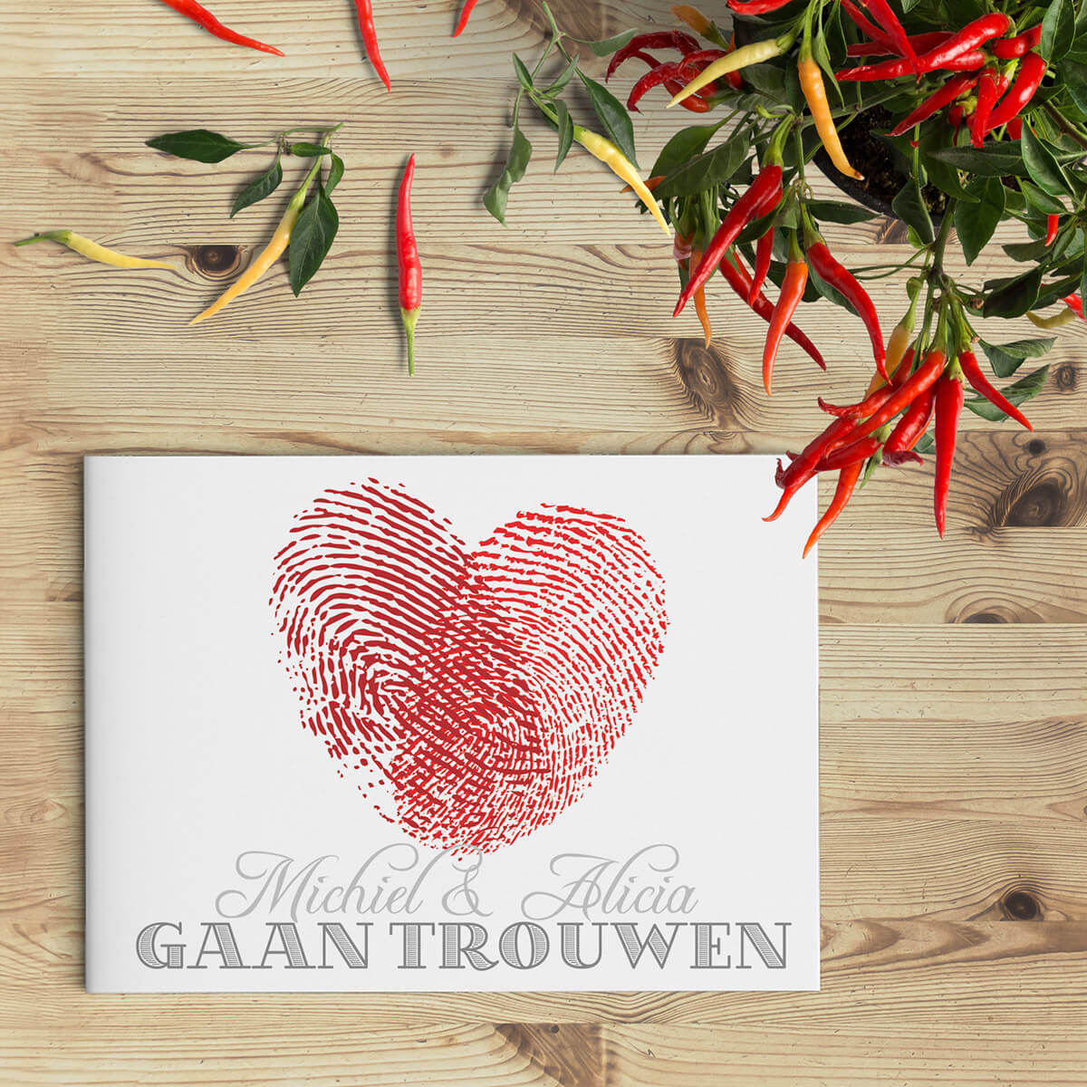 Modern trouwkaartje met hart gevormd door twee vingerafdrukken. Rood en grijs van kleur.
